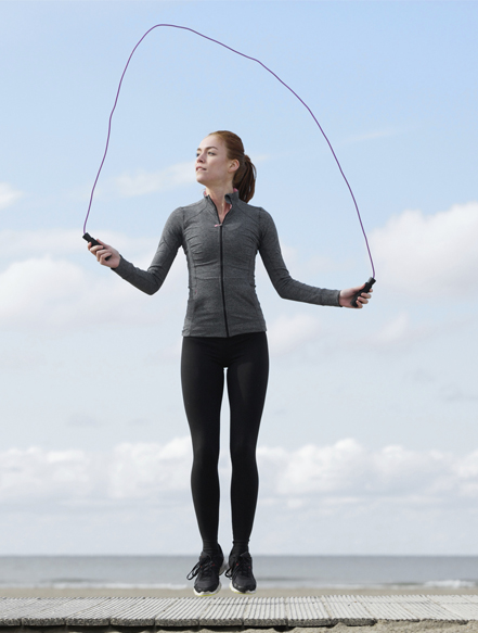 "Person jumping rope outdoors as part of a travel fitness routine with a scenic background"